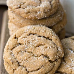 A soft ginger molasses cookie leaning against a stack of cookies.