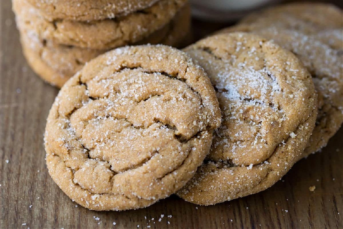 Overlapping molasses cookies on a wooden cutting board. 