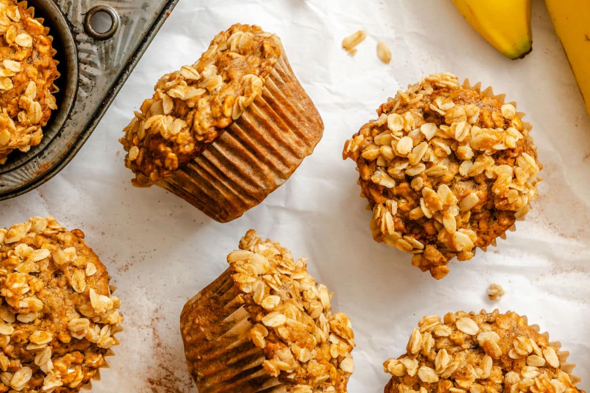 Banana oatmeal muffins on white parchment paper next to the pan.