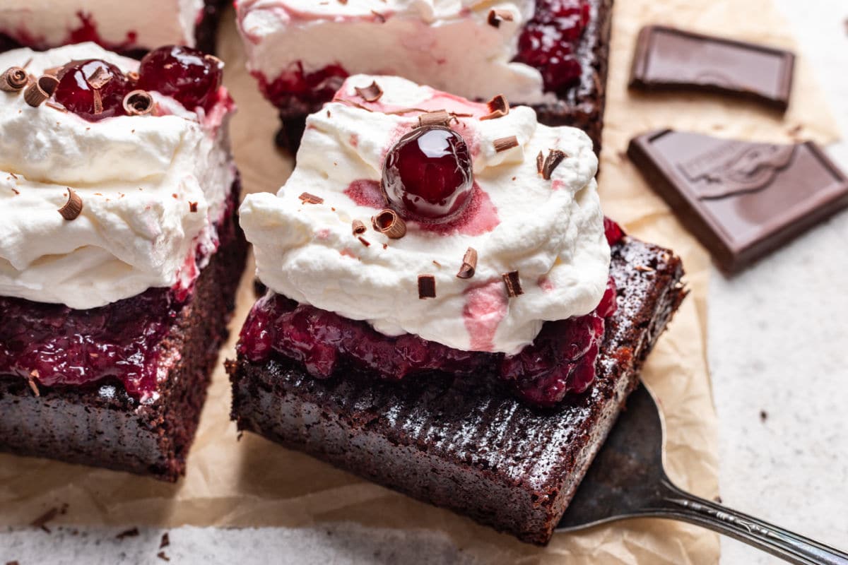 A cake server removing a piece of Black Forest sheet cake from the cake.