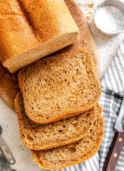 Three slices of steakhouse brown bread sliced next to the loaf.