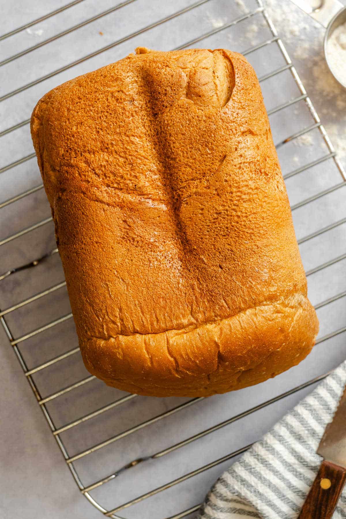 A loaf of bread machine bread on a wire cooling rack. 