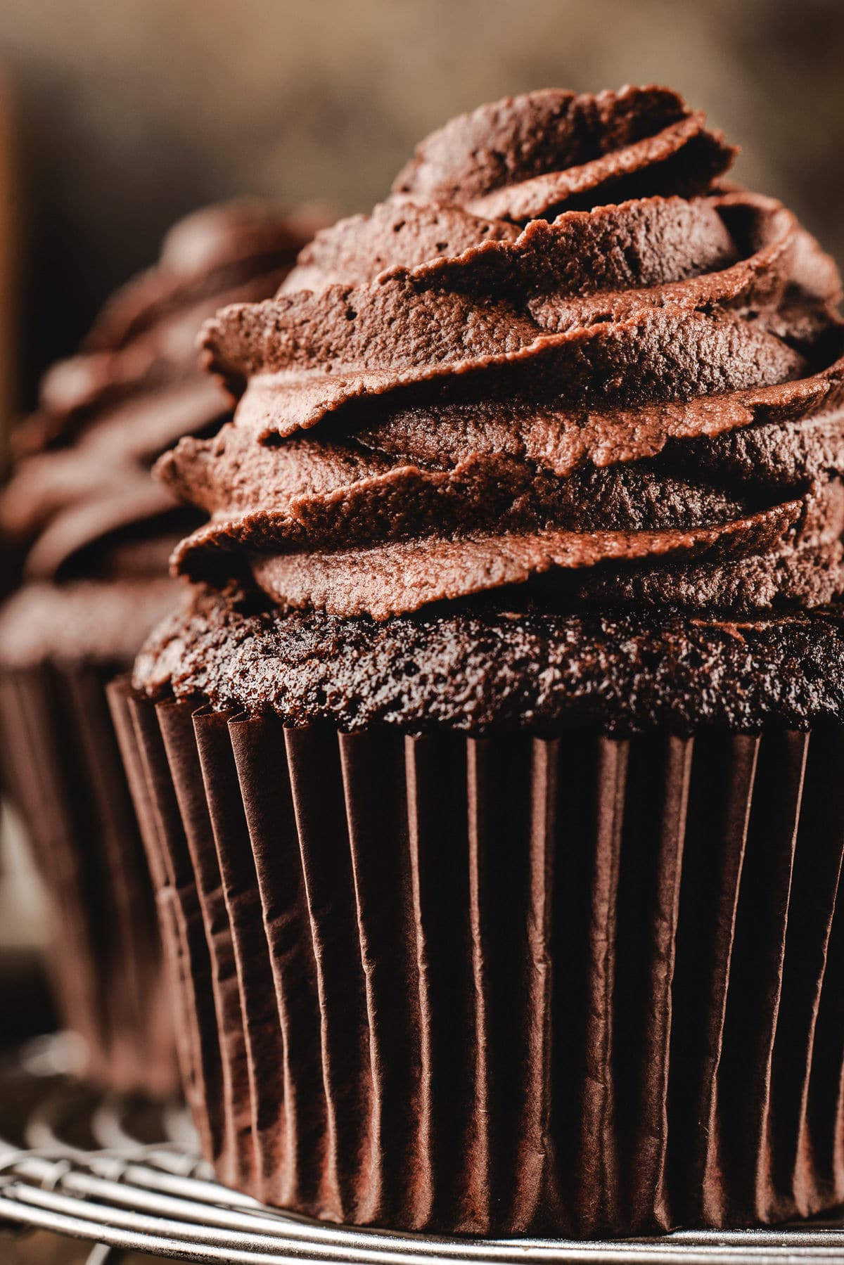 Two close up chocolate cupcakes topped with piped chocolate buttercream.