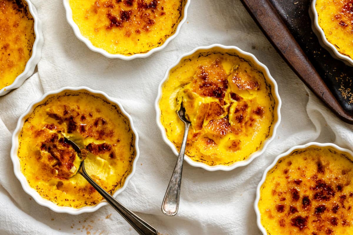 Ramekins of creme brulee with silver spoons in them.