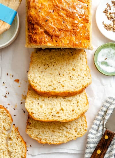 A loaf of dilly bread with three slices cut from it.