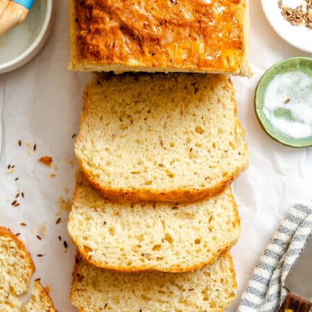 A loaf of dilly bread with three slices cut from it.