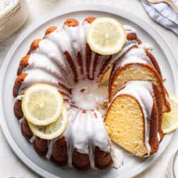 A partially sliced iced lemon pound cake on a platter.
