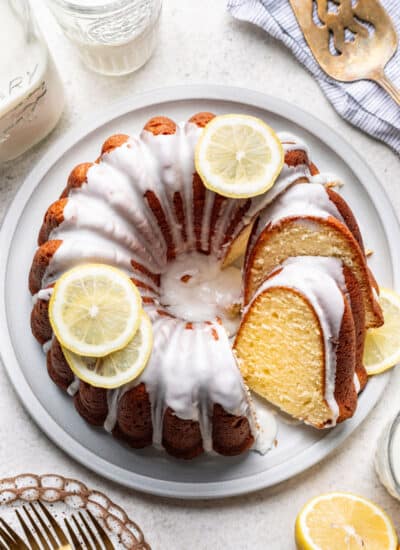 A partially sliced iced lemon pound cake on a platter.