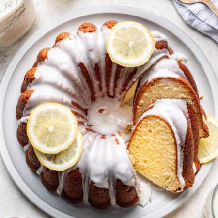 A partially sliced iced lemon pound cake on a platter.