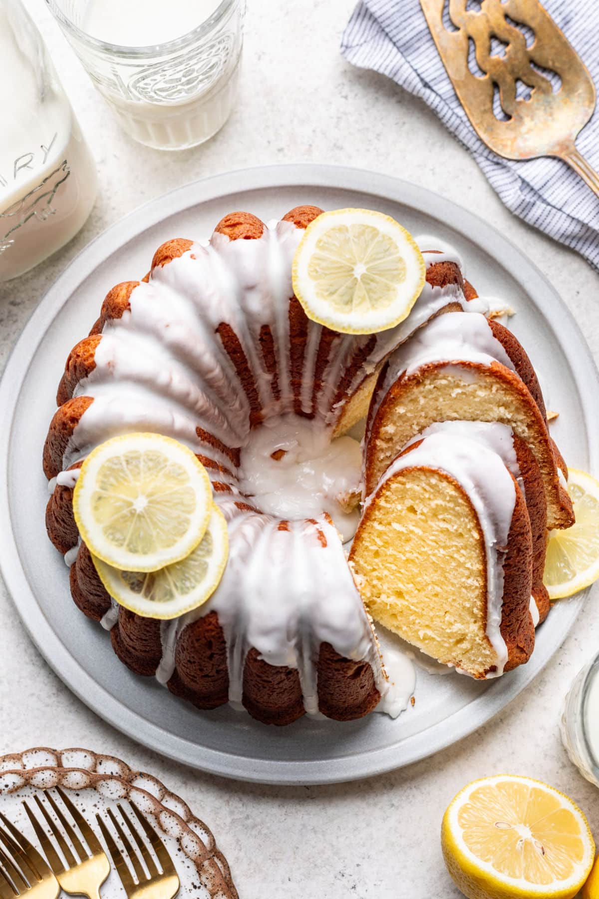 A partially sliced iced lemon pound cake on a platter.