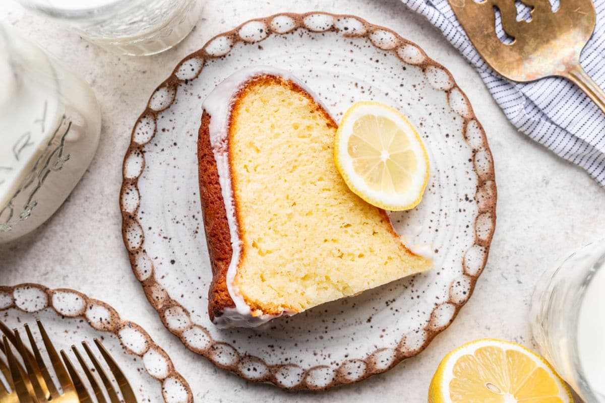 A slice of iced lemon pound cake and a lemon slice on a plate.