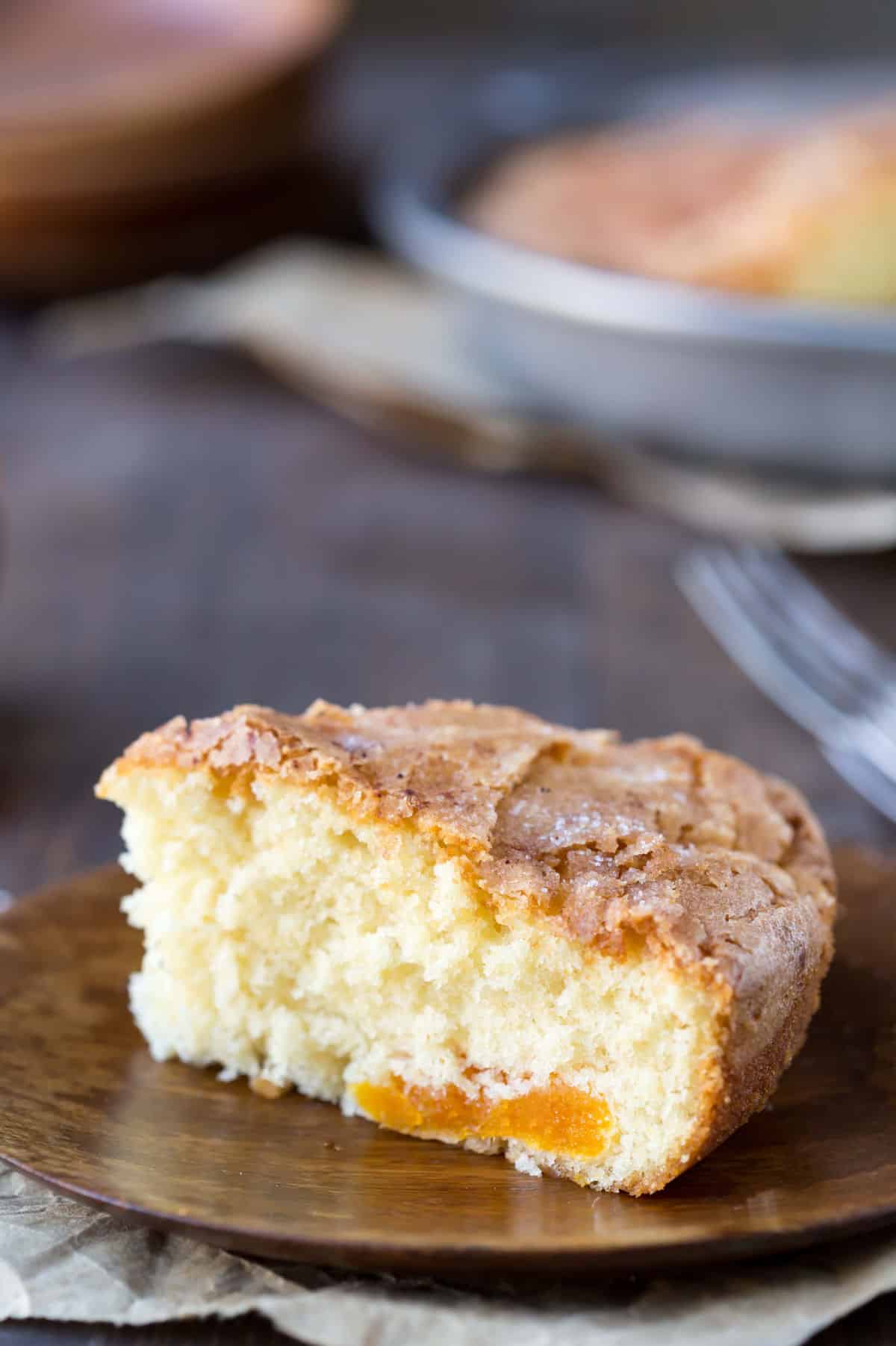 Slice of Apricot Kuchen on a wooden plate.