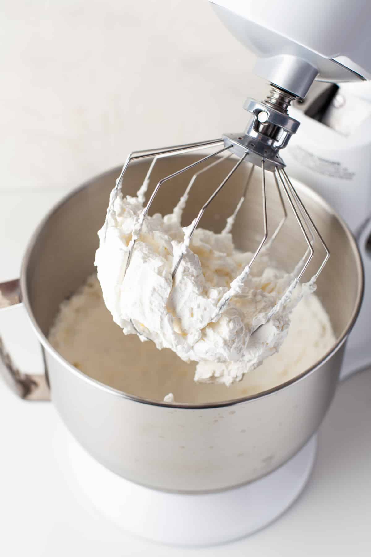Homemade whipped cream on a whisk attachment of a stand mixer.