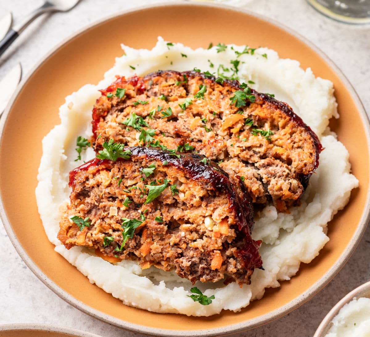 Two slices of air fryer meatloaf on a plate with mashed potatoes.