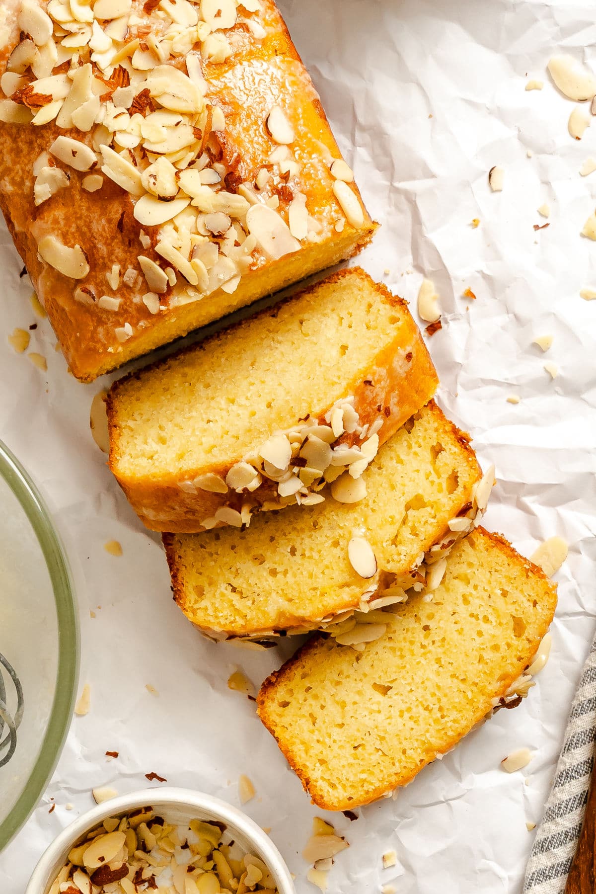 Three slices of almond quick bread next to the loaf.