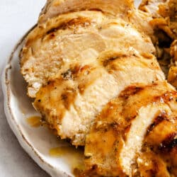 Sliced grilled Caesar-marinaded chicken on a plate.