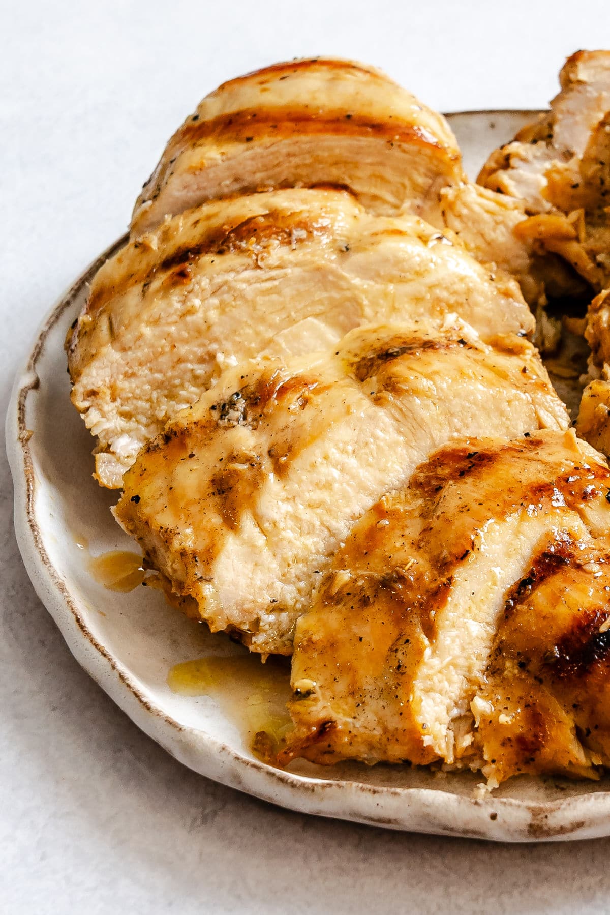 Sliced grilled Caesar-marinaded chicken on a plate.