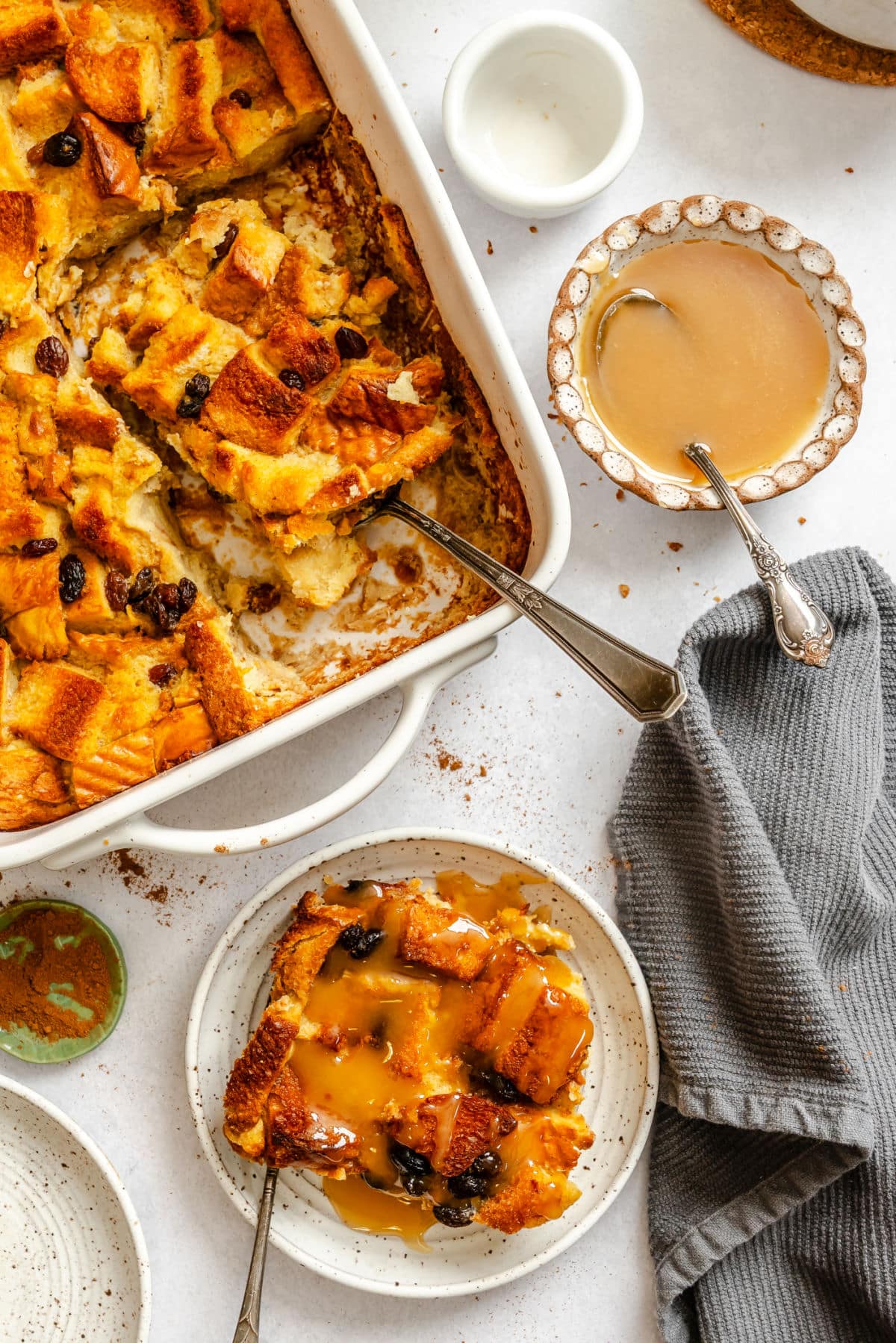 A plate of Irish bread pudding topped with sauce next to the pan.