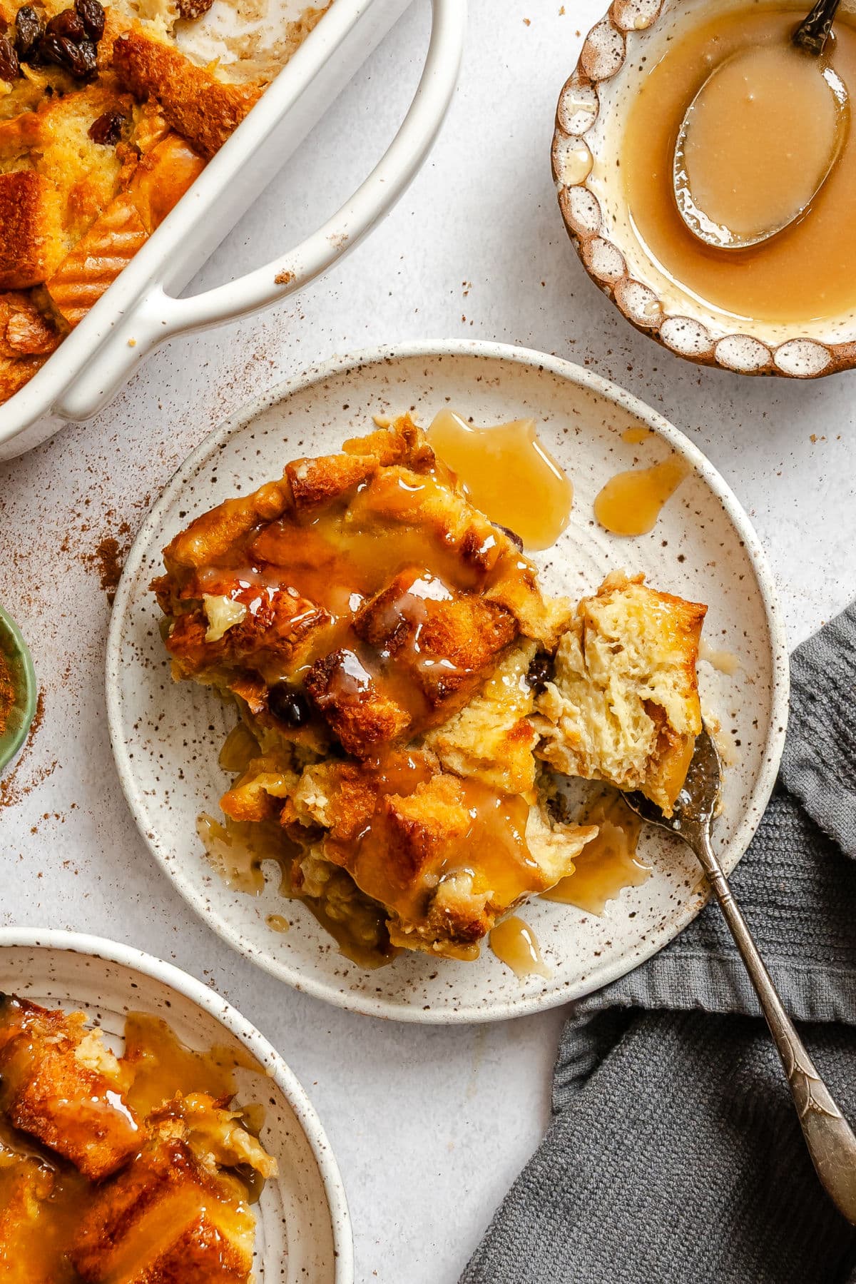 A fork holding a bite of Irish bread pudding next to the rest of the piece. 