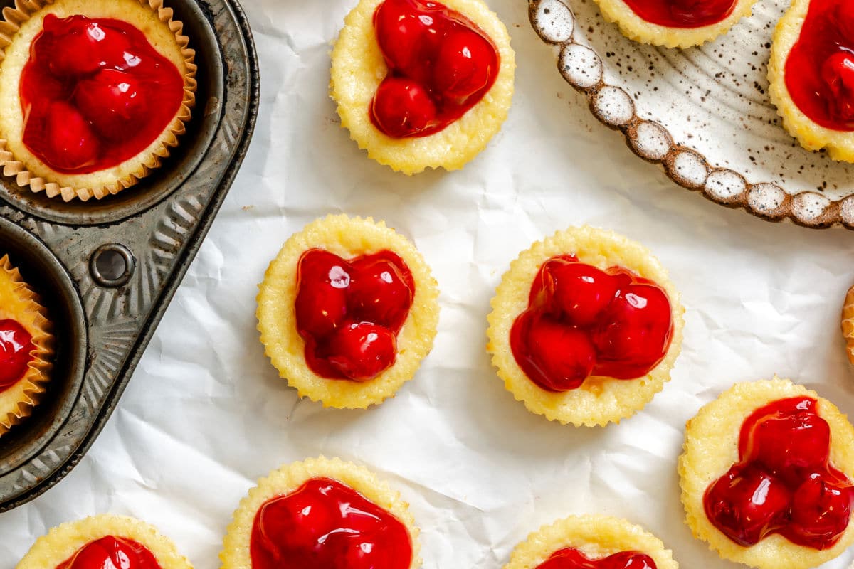 Mini cherry cheesecakes on a piece of white parchment paper.