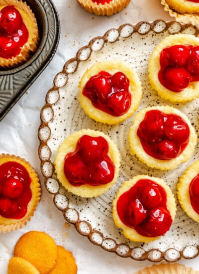 A platter of mini cherry cheesecakes next to the muffin tin.