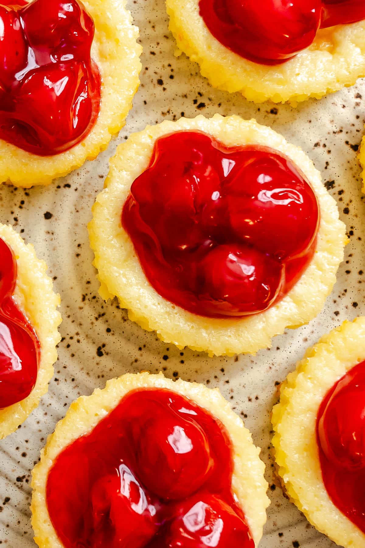 Cherry cheesecakes unwrapped on a platter.