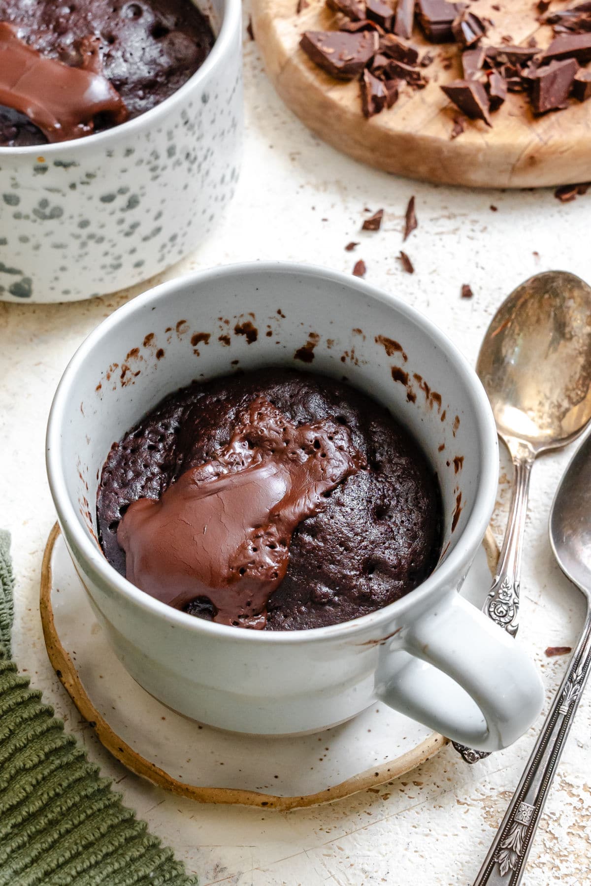 Molten Chocolate Mug Cake A chocolate lava molten cake in a mug next to pieces of baking chocolate.