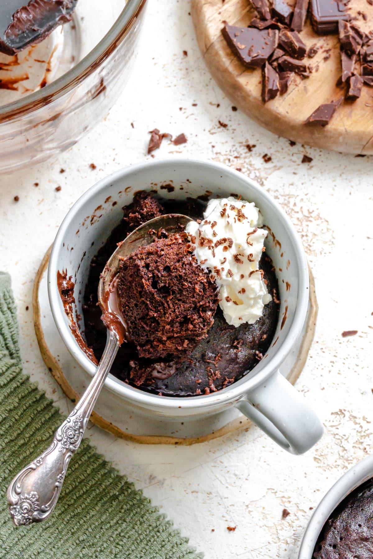 Chocolate Mug Cake Recipe A spoon of chocolate lava mug cake and whipped cream in a mug.