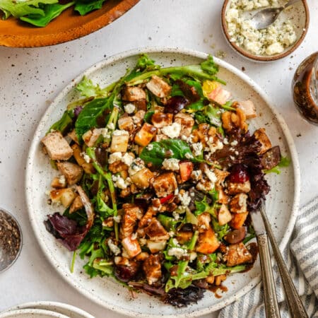 California Pizza Kitchen copycat waldorf salad on a plate next to dishes of gorgonzola and a dish of a dressing.