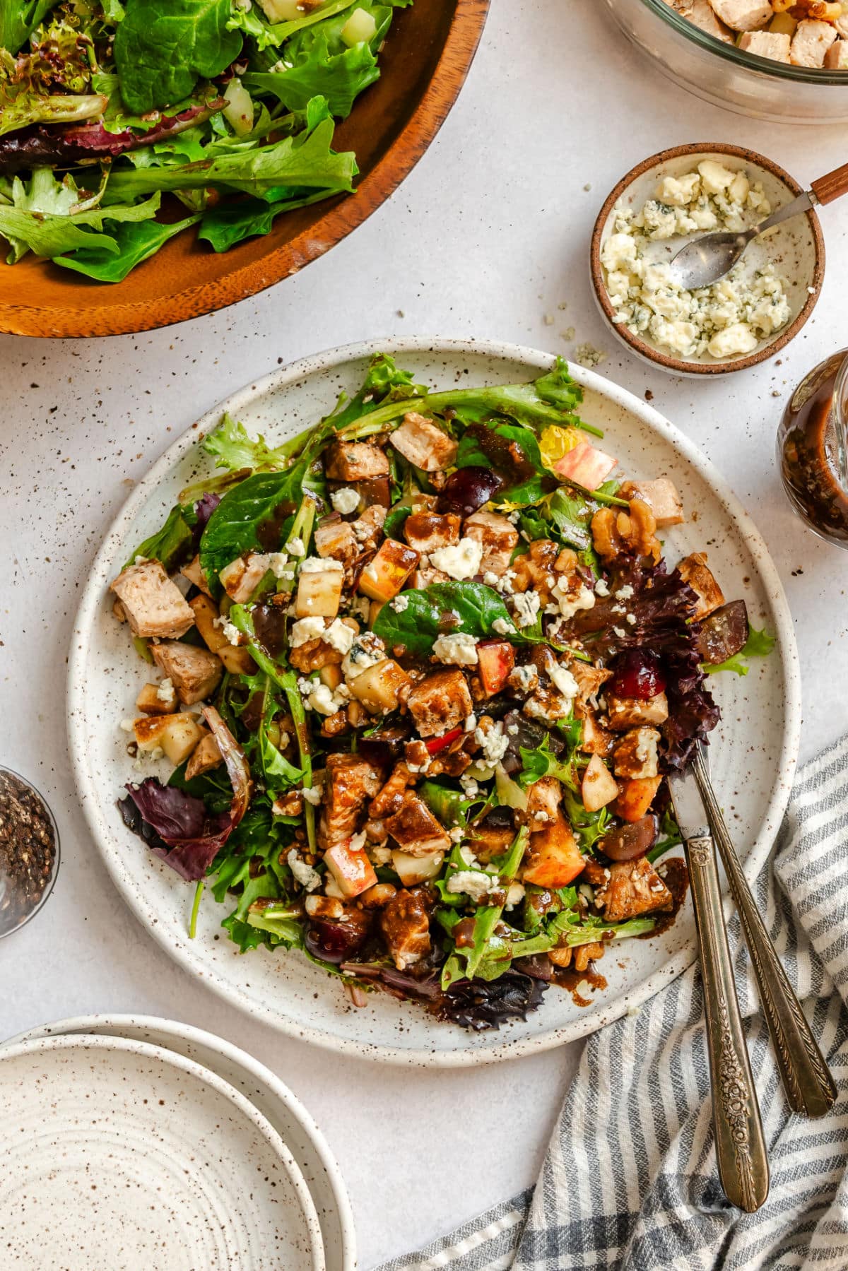 California Pizza Kitchen copycat waldorf salad on a plate next to dishes of gorgonzola and a dish of a dressing.