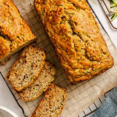 A loaf of zucchini banana bread next to a partially sliced loaf.