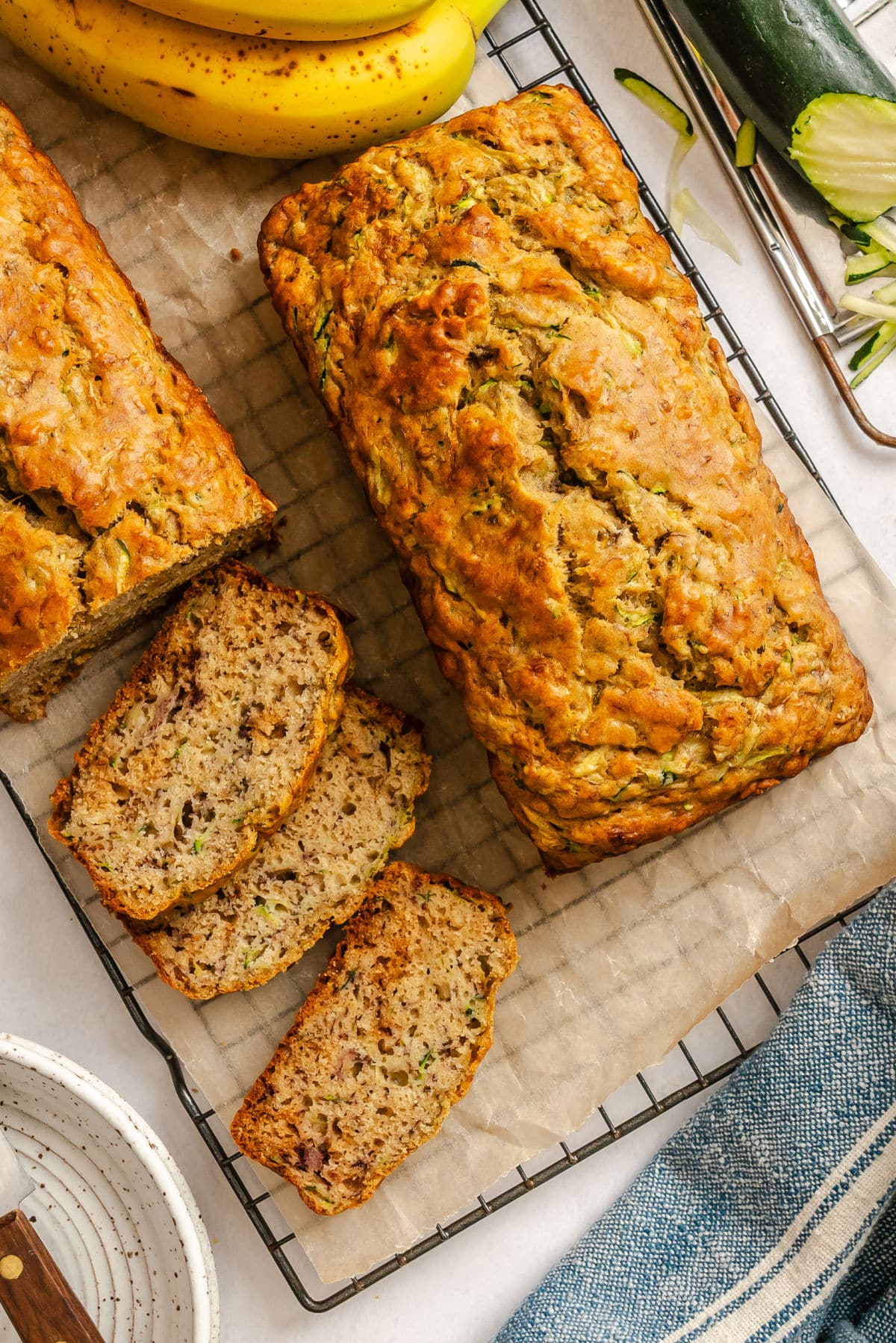 A loaf of zucchini banana bread next to a partially sliced loaf.