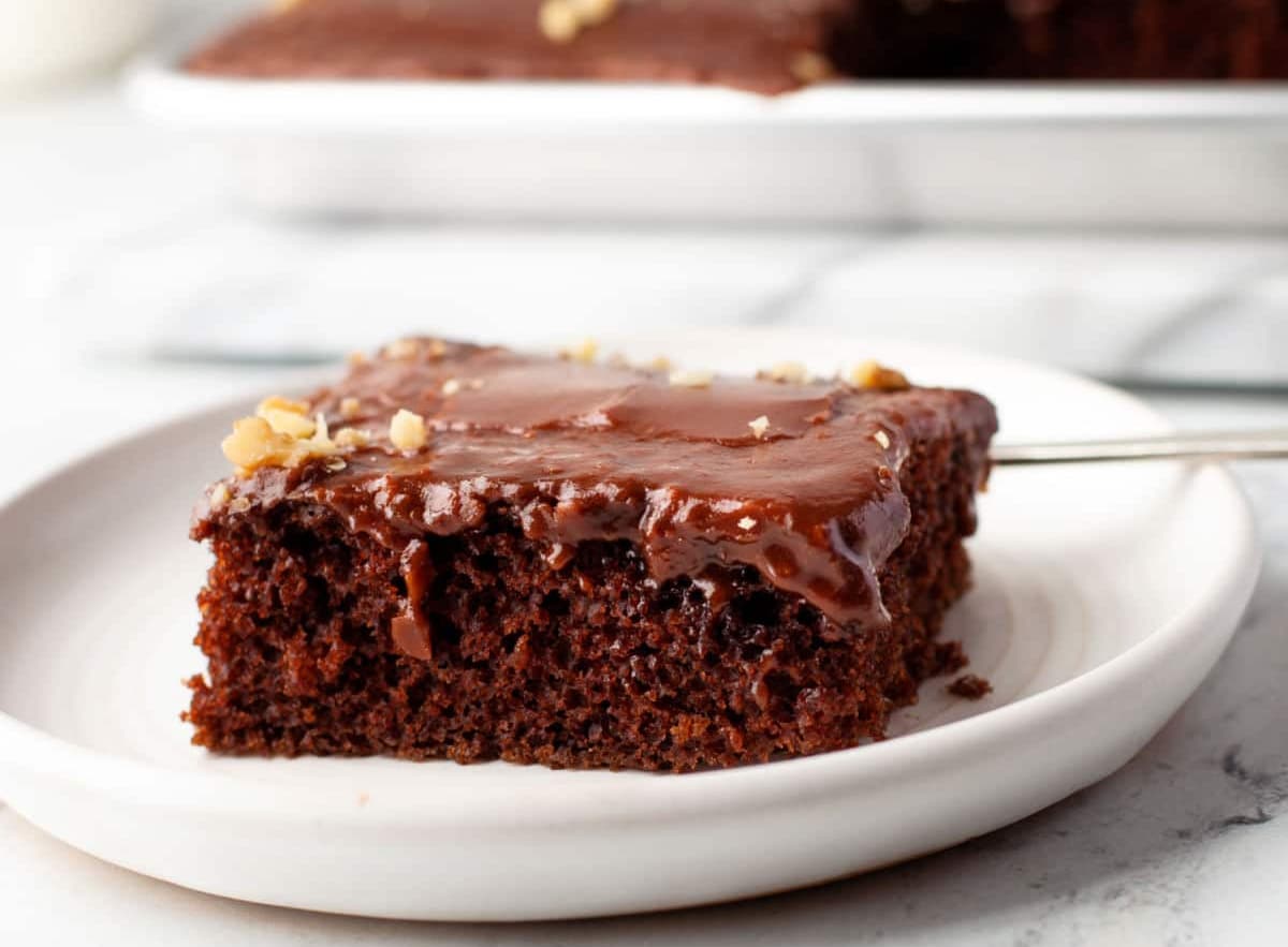 A piece of Texas sheet cake on a plate next to the pan of cake.