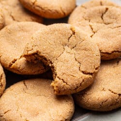 A plate of brown sugar cookies with one with a bite missing.
