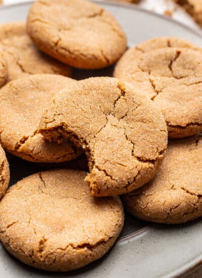 A plate of brown sugar cookies with one with a bite missing.
