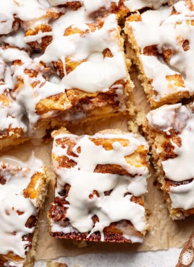 Pieces of cinnamon roll cake on a piece of brown parchment paper.