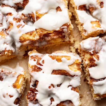 Pieces of cinnamon roll cake on a piece of brown parchment paper.