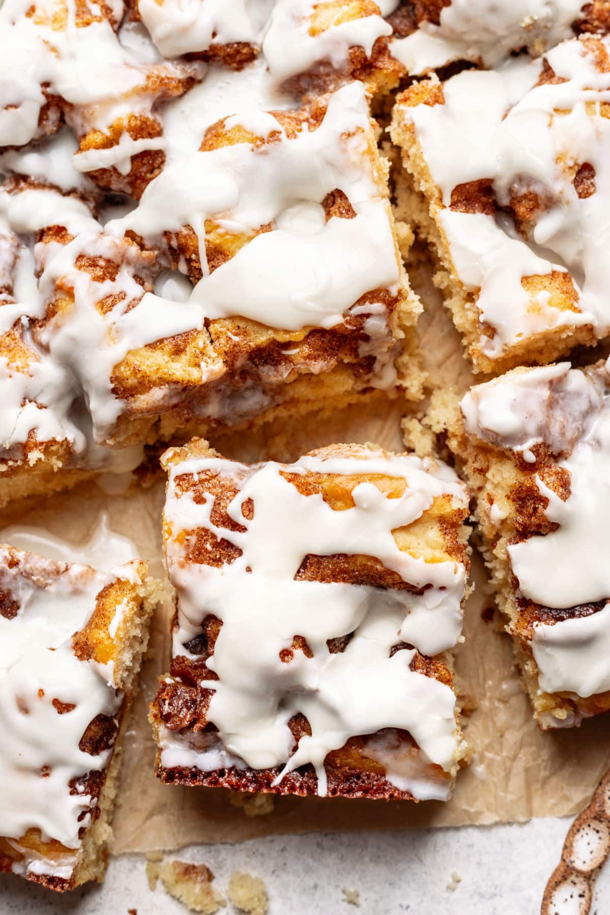 Pieces of cinnamon roll cake on a piece of brown parchment paper.