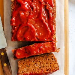Two slices of meatloaf next to the rest of the meatloaf.