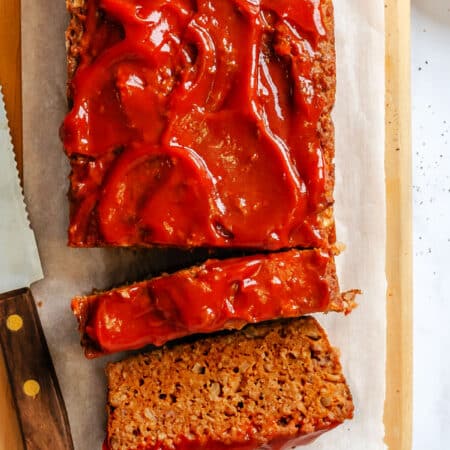 Two slices of meatloaf next to the rest of the meatloaf.