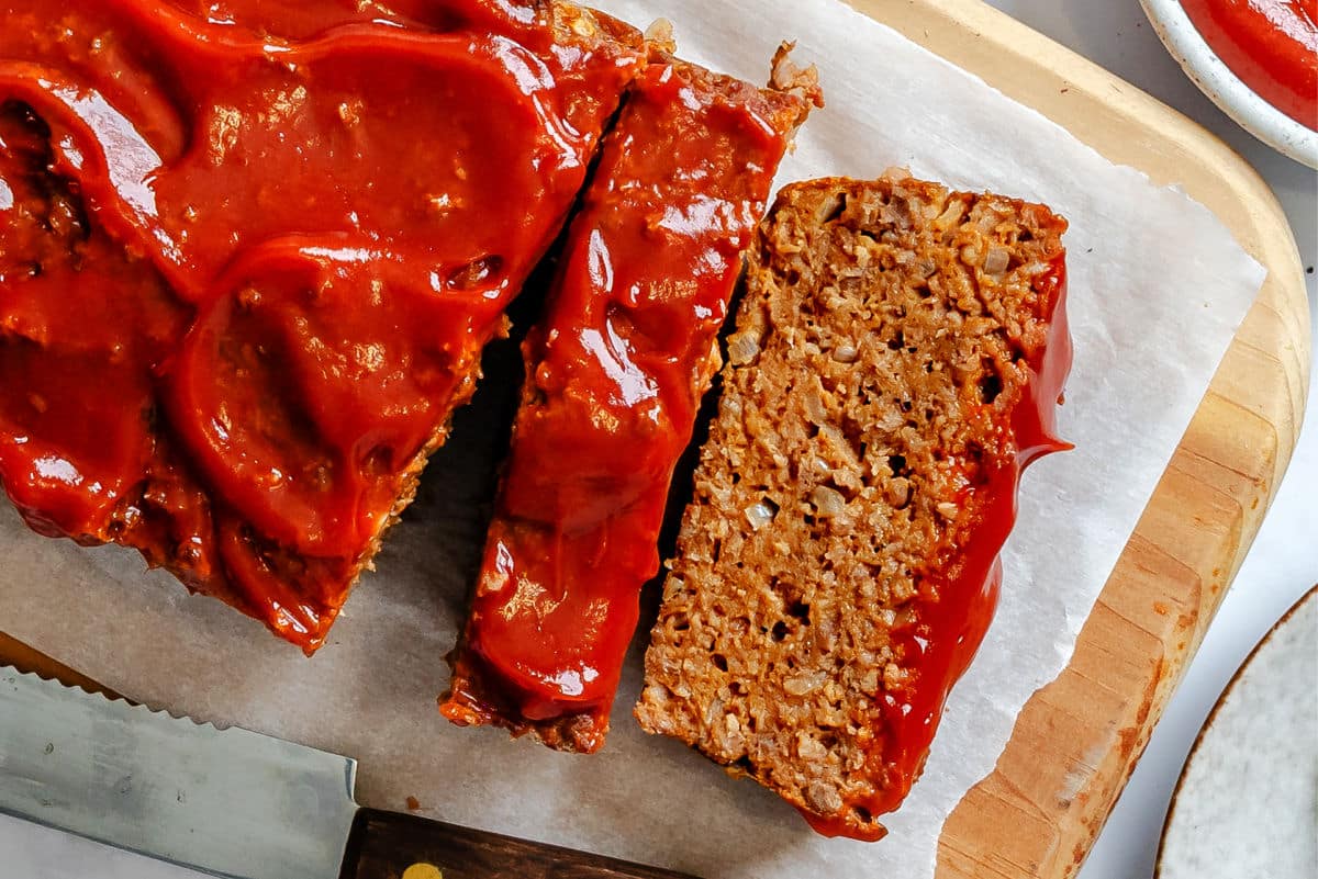 Slices of meatloaf on a parchment lined cutting board.