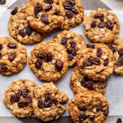 Overlapping brown butter oatmeal raisin cookies on a round cutting board.