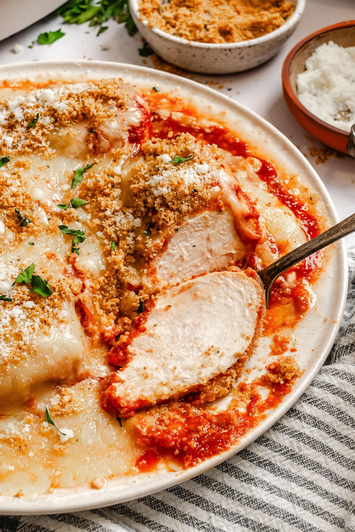 A partially sliced piece of chicken parmesan on a plate.