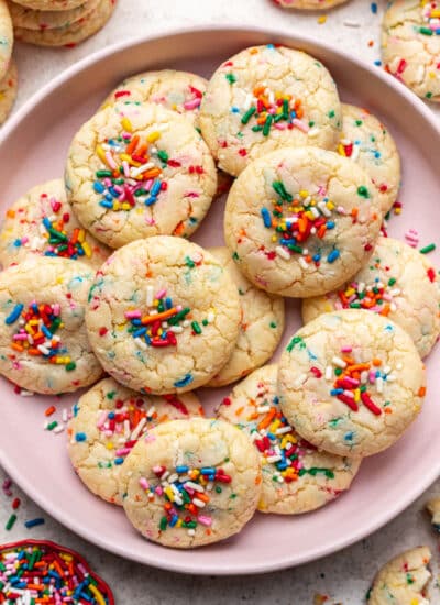 A pink plate with overlapping sprinkle cookies on it.