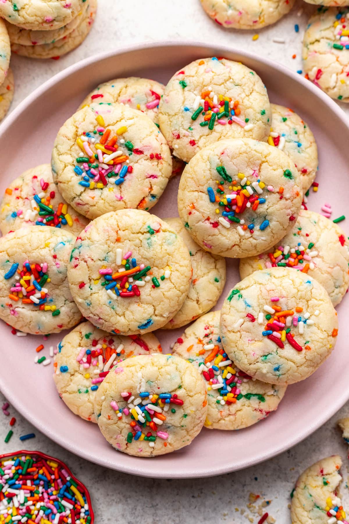A pink plate with overlapping sprinkle cookies on it.