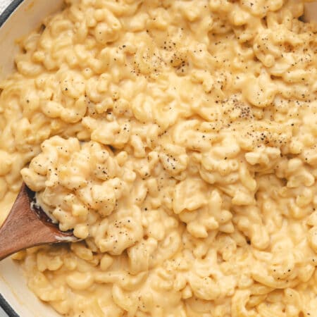 A wooden spoon in a pot of homemade mac and cheese.