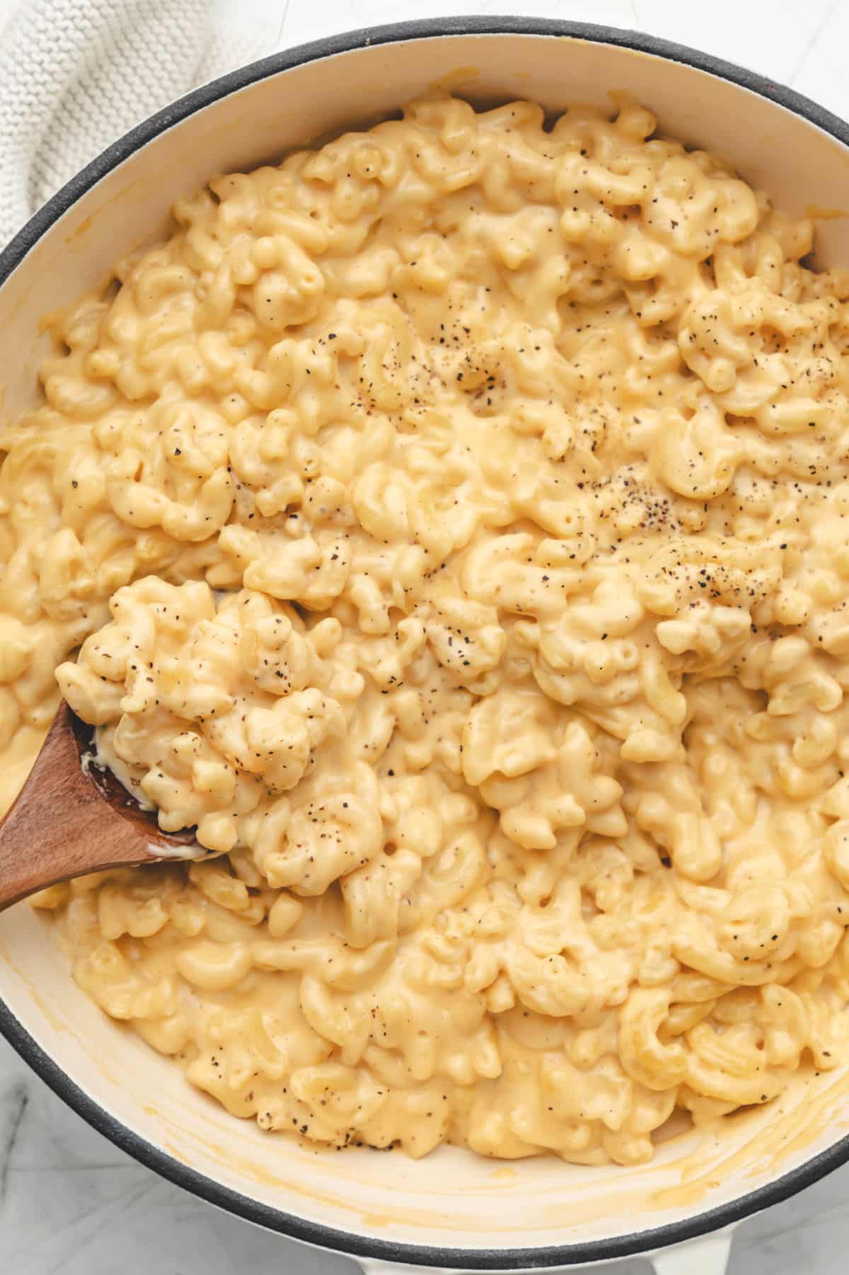 A wooden spoon in a pot of homemade mac and cheese.