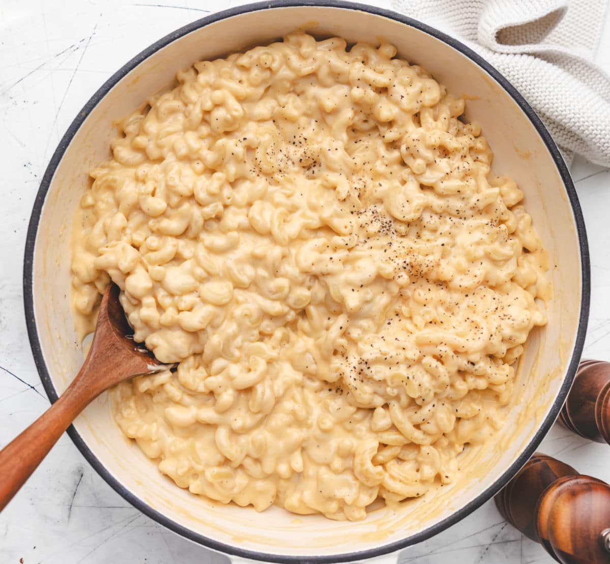 A Dutch oven with homemade mac and cheese and a wooden spoon in it. 