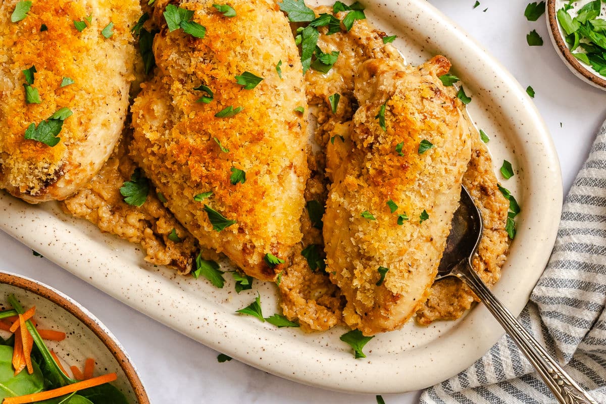 Baked Caesar chicken breasts on a serving platter. 