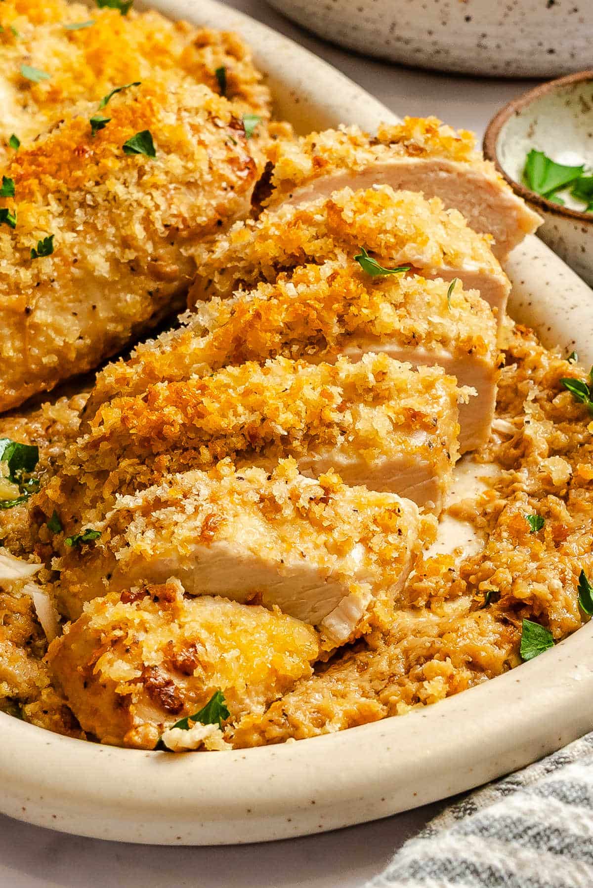 Sliced baked Caesar chicken breast on a serving platter. 